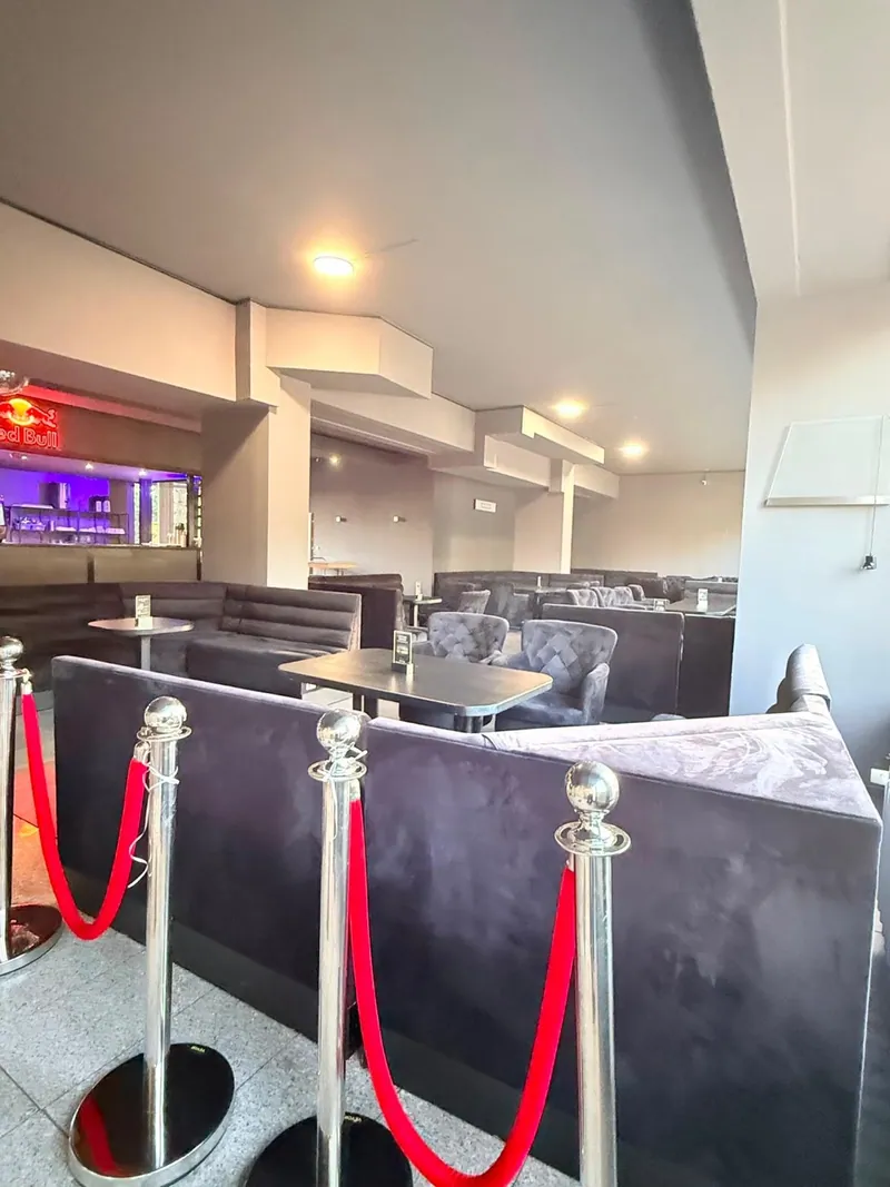 Kontrast-Lounge bei Tageslicht mit dunklen Sitzgruppen und roter Absperrkordel