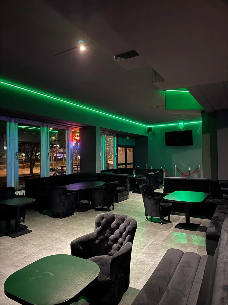 Lounge der Kontrast-Bar mit grüner Deckenbeleuchtung und dunklen Sesseln