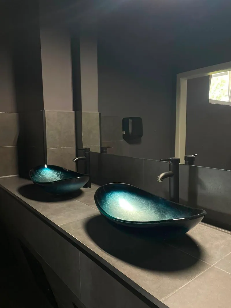 Dunkle türkisfarbene Waschbecken im WC-Bereich der Kontrast-Bar
