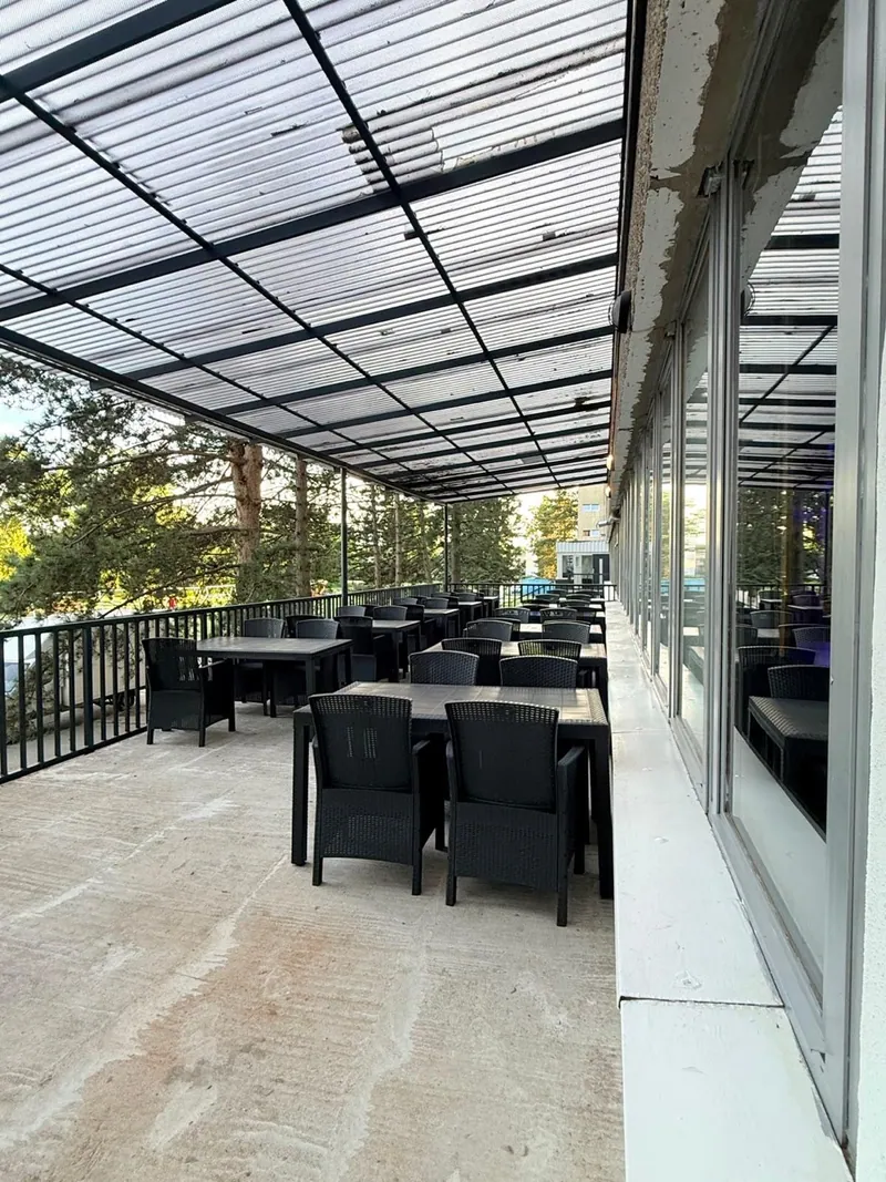 Überdachte Ootel-Terrasse mit schwarzen Tischen und Stühlen
